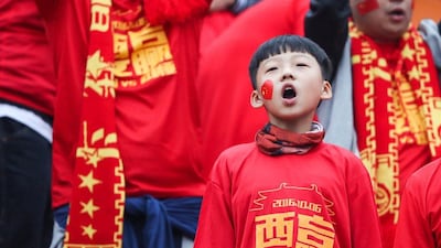 Fans cheer ahead of match between China and Syria. The Chinese characters read, “We shall win”. Stringer / Reuters