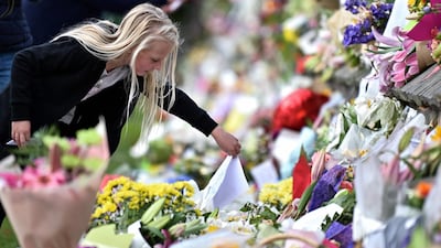 A young girl places a note among flowers left in tribute to the Christchurch victims. AFP