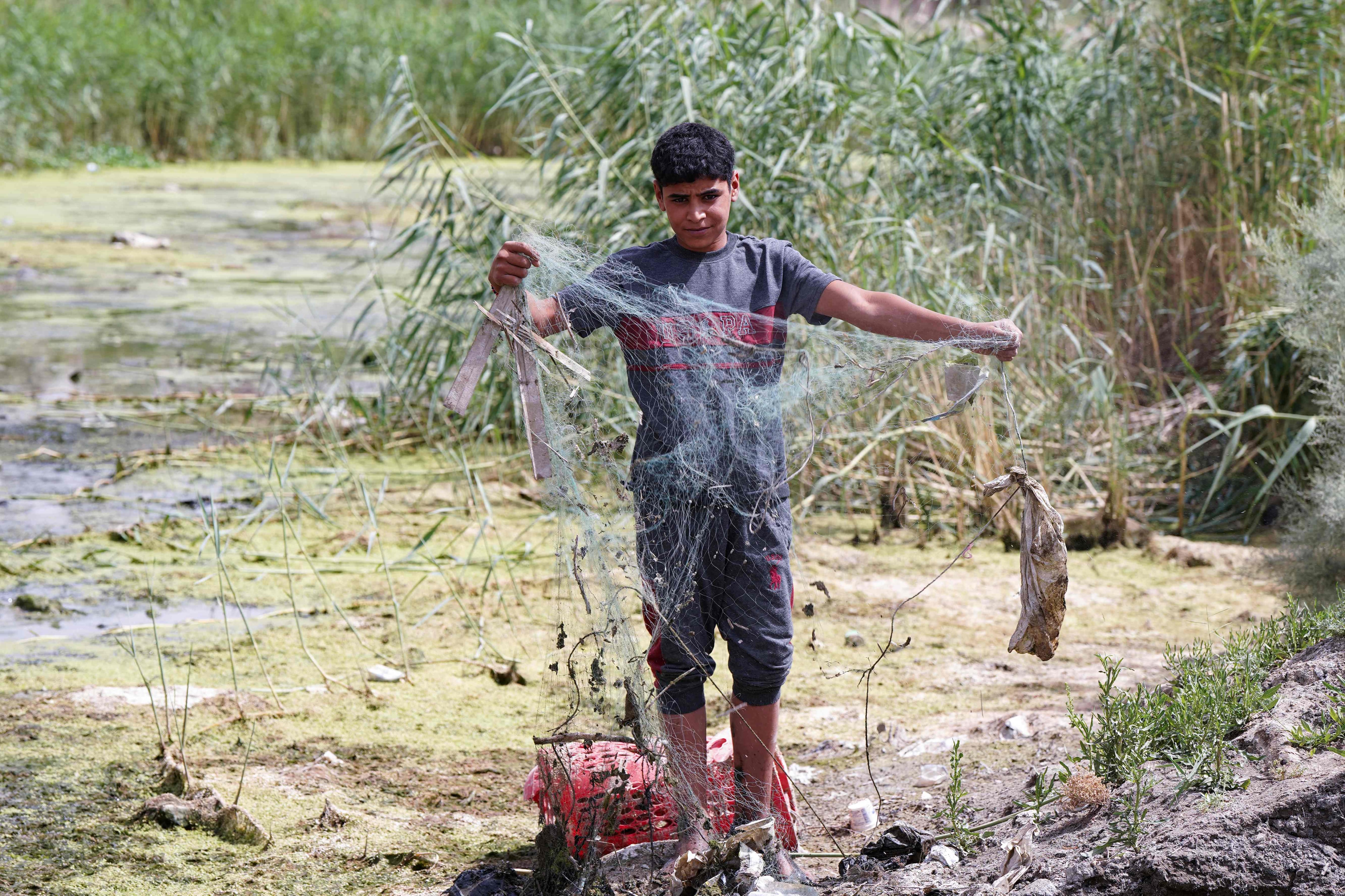 A boy untangles a net as he stands fishing in an almost dried-up stream in Mishkhab, in Najaf province, Iraq, where years of drought have depleted the fauna and flora. All photos: AFP