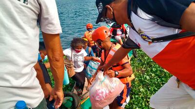 Families are evacuated by members of the Philippine Coast Guard to safer ground in Camarines Sur province, eastern Philippines. Philippine Coast Guard via AP
