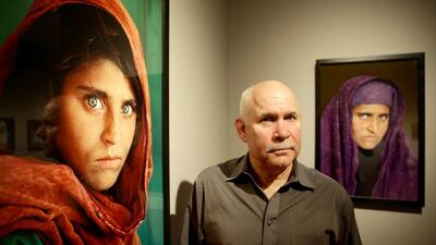 US photographer Steve McCurry poses next to his photos of the "Afghan Girl" named Sharbat Gula at the opening of the "Overwhelmed by Life" exhibition of his work at the Museum for Art and Trade in Hamburg, northern Germany on June 27, 2013. Gula was arrested in Pakistan on October 26, 2016 for owning a fake ID card. Ulrich Perrey / AFP Photo