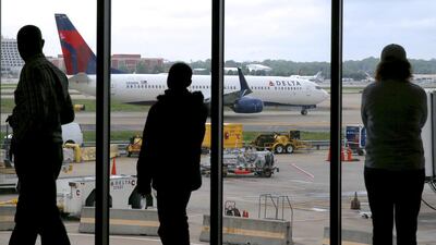 Delta passengers watch as a plane taxis at Atlanta’s Hartsfield International Airport. Charles Rex Arbogast / AP Photo