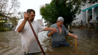 Terry Panchot, left, helps Charles Cormier walk through floodwaters in front of their home in Galveston, Texas, in the aftermath of Hurricane Ike on Sept 13.