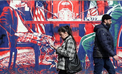 Iranians walk past an anti-US mural showing a negotiation table in Tehran. EPA
