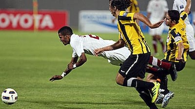 Al Wahda's Mahmoud Al Hammadi is tripped up by, and Al Ittihad's defence.