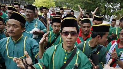 A Muslim group dressed in uniform recites a prayer during a a protest against the use of the word 'Allah' by a Christian weekly magazine as a translation of 'God'. EPA/Shamshahrin Shamsudin
