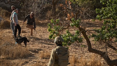 Israeli settlers watch as Israeli soldiers block access for Palestinians to an olive grove in the West Bank village of Sa'ir. AP