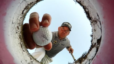 Lee Westwood of England takes a ball out of a golf hole on the putting green during a practice round prior to the Omega Dubai Desert Classic at the Emirates Golf Club in Dubai. Ross Kinnaird/Getty Images