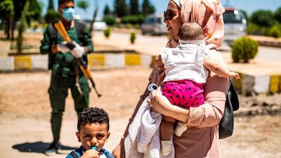 Passengers, who were stranded following the closure of border due to the pandemic, disembark a bus upon their arrival from Iraqi Kurdistan to the Syrian side of the Semalka border crossing in northeastern Syria. AFP