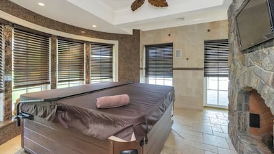 The hot tub sits in front of a TV - and another fireplace. Courtesy Douglas Elliman Realty