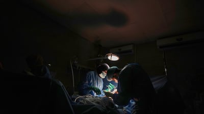 Dr Abeer Al Gharbawi, left, performs surgery under the illumination of a battery-powered light during a blackout