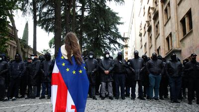 A protester wearing a composite of the Georgian and European flags faces policemen blocking a street during a rally against a draft bill on 'foreign agents' near the parliament building in Tbilisi, Georgia. EPA