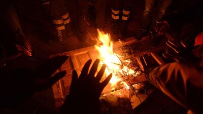 Turkish officials and police try to keep warm at the scene of a collapsed building following a 6.8 magnitude earthquake in Elazig, eastern Turkey. AFP