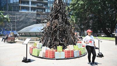 A volunteer collects donations in front of an an installation dubbed 'the Burnt Christmas Tree' to support the Australian Red Cross’ Disaster Relief and Recovery Fund in Sydney. AFP