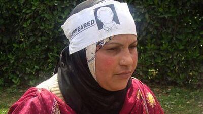 Tahira Begam holds a picture of her husband, Tariq Ahmad Rather, who disappeared in 2002 from his home in Baramulla, and left, an unmarked grave in Kupwara.