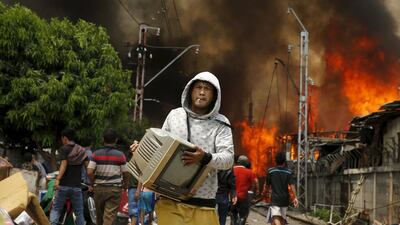A man carries a television away from a fire in a slum area next to railway tracks in Kampung Bandan, North Jakarta, Indonesia. According to local media, the fire destroyed approximately 100 wooden dwellings, built along a busy railway line. No casualties were reported. Beawiharta / Reuters