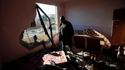 A Palestinian man looks out of his apartment that was damaged in an Israeli airstrike at a nearby militant target. Mohammed Salem / Reuters.