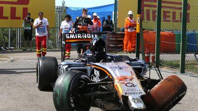 Nico Huelkenberg, centre, examines his damaged Force India racer. Ferenc Isza / AFP