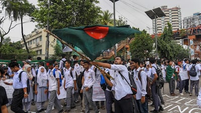 A Bangladeshi student wave Bangladesh's national flag as they block a road during a student protest in Dhaka. AFP PHOTO / MUNIR UZ ZAMAN