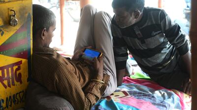 Indian Priest Chandan Mishra, 35, plays a game on his smartphone as he waits for devotees at the Sangam area in Allahabad. AFP