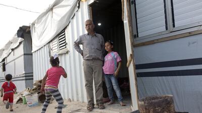 Mohammed Najjar, 48, stands with his family outside the caravan he is living in at the encampment in Khuza'a in the Gaza Strip on April 20, 2015. Heidi Levine for The National