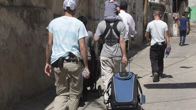 Two armed Israeli guards escort a Jewish family in the street of the Batin Al Hawa section in Silwan.