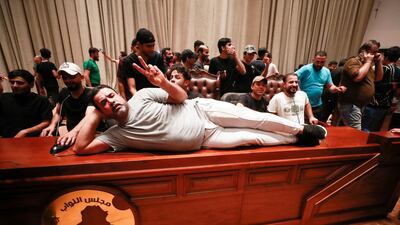 A demonstrator lies on the desk of the Speaker of the Iraqi parliament. AFP