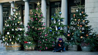A woman sits amid Christmas trees in Covent Garden, in London. AP Photo