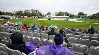 People wait in their seats as groundsmen work on the wet pitch at Malahide. Paul Faith / AFP