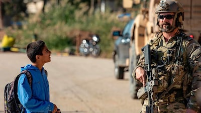 A Syrian boy looks at a US soldier on patrol in the village of Ein Diwar in Syria's northeastern Hasakeh province. AFP
