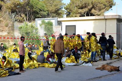 Migrants wake up after spending the night outside a migrant housing center on Lampedusa. AP