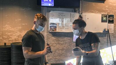 Keith O'Donnell gives green pass proof from Al Hosn application at Vogue Fitness, Yas Marina. Khushnum Bhandari / The National