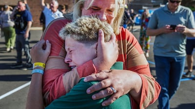 A parent hugs her son. AP