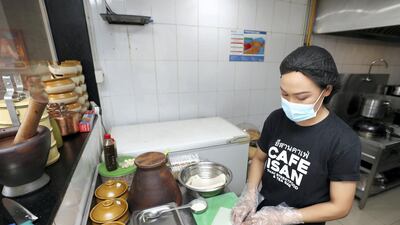 Chef New adheres to safety measures while preparing vegetable spring rolls at a Dubai restaurant. Chris Whiteoak / The National