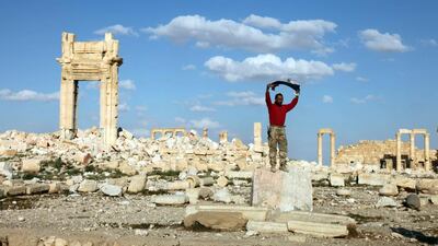 A Syrian soldier stands with the Syrian flag inside the historical ancient city of Palmyra after regaining control from ISIS. EPA