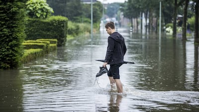 A man paddles along a flooded street near the De Dem water buffer in Hoensbroek, Limburg, the Netherlands.