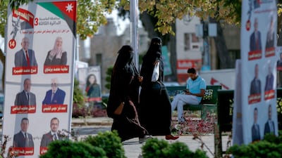 Women walk in a park filled with campaign posters and slogans of candidates for the upcoming Jordanian parliamentary elections line a street in the capital Amman. AFP