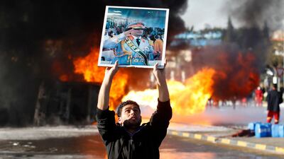 A man holds up a poster of Libya's leader Muammar Gaddafi, one of several distributed among a crowd gathered to view a burning fuel truck, in Tripoli in this March 2, 2011 file photo. REUTERS/Chris Helgren/Files (LIBYA - Tags: CONFLICT POLITICS MILITARY)