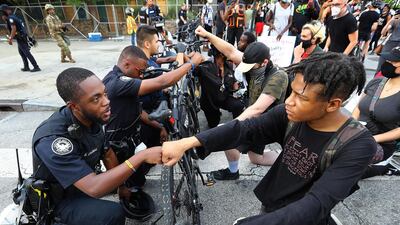 Atlanta Police Officer J. Coleman, left, and protester Elijah Raffington, of Sandy Springs, fist bump while an Atlanta Police bicycle unit blocking Marietta Street at Centennial Olympic Park Drive kneels down with protesters in a symbolic gesture of solidarity outside the CNN Center at Olympic Park, in Atlanta, during a protest sparked by the May 25 death of George Floyd in Minneapolis police custody. AP