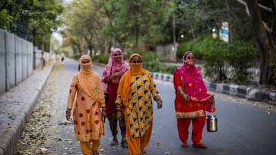 Indian women carry containers to buy milk as they walk on a deserted road amid a nationwide lockdown, in New Delhi, India. Getty Images