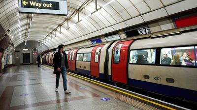 A passenger wearing a face mask walks along the platform as an underground train approaches, in London. AP Photo