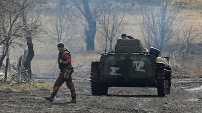 A pro-Russian soldier in a uniform without insignia walks next to an armoured vehicle with "Z" painted on its side in the separatist-controlled village of Bugas, Ukraine. Reuters