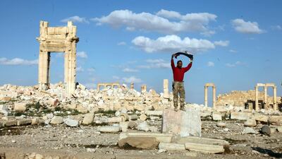 A Syrian soldier raises the national flag as he stands amid the rubble of the historical city of Palmyra, last week. EPA