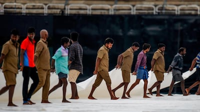 Ground staff cover the pitch after a drizzle at the MA Chidambaram Stadium in Chennai. AFP