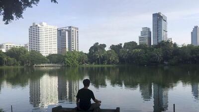 A man meditates on a bench in front of a lake in Lumphini Park in Bangkok, Thailand. Charles Dharapak / AP Photo