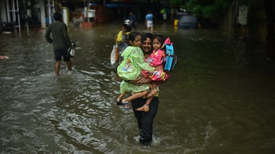 A father in Chennai carries his children to safety. EPA