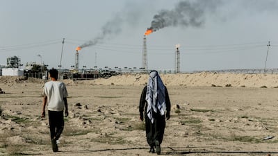 People walk near farmland by the Zubair oil field as gas flares rise in the distance, in Zubair Mishrif, Basra. Reuters