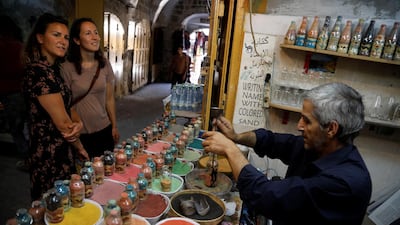 Tourists look on as Palestinian craftsman Mohammed Al-Awawda creates coloured sand artworks at his souvenir shop in Hebron, in the Israeli-occupied West Bank. Reuters