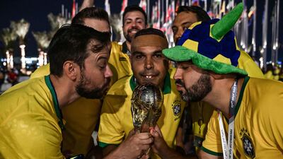 Brazil fans — including a lookalike of Brazilian legend Ronaldo — pose with a replica of the World Cup trophy at Flag Plaza in Doha. AFP