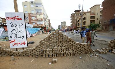 Sudanese protesters stand behind road blocks as they take part in an anti-military demonstration. AFP